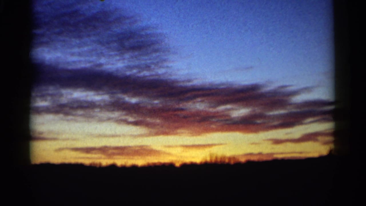 1961 Minnesota home-movie view of rolling purple clouds over yellow-orange sunset light and a dark horizon.