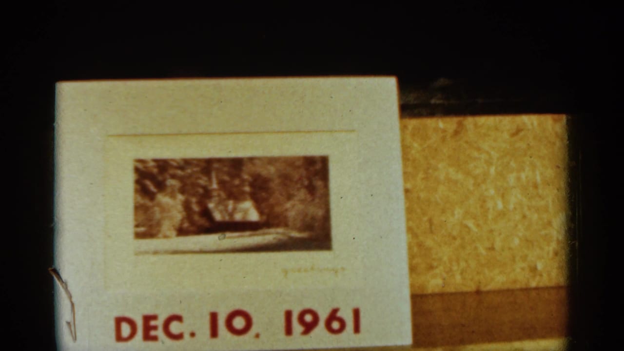 Dated 1961 title card on 8mm film, showing red date text and a small snowy outdoor photograph or frame.