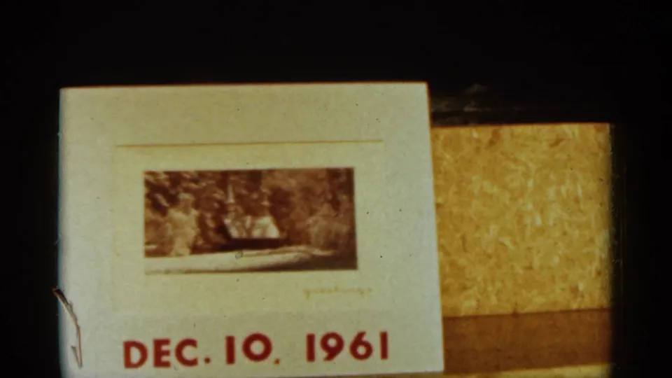 Dated 1961 title card on 8mm film, showing red date text and a small snowy outdoor photograph or frame.