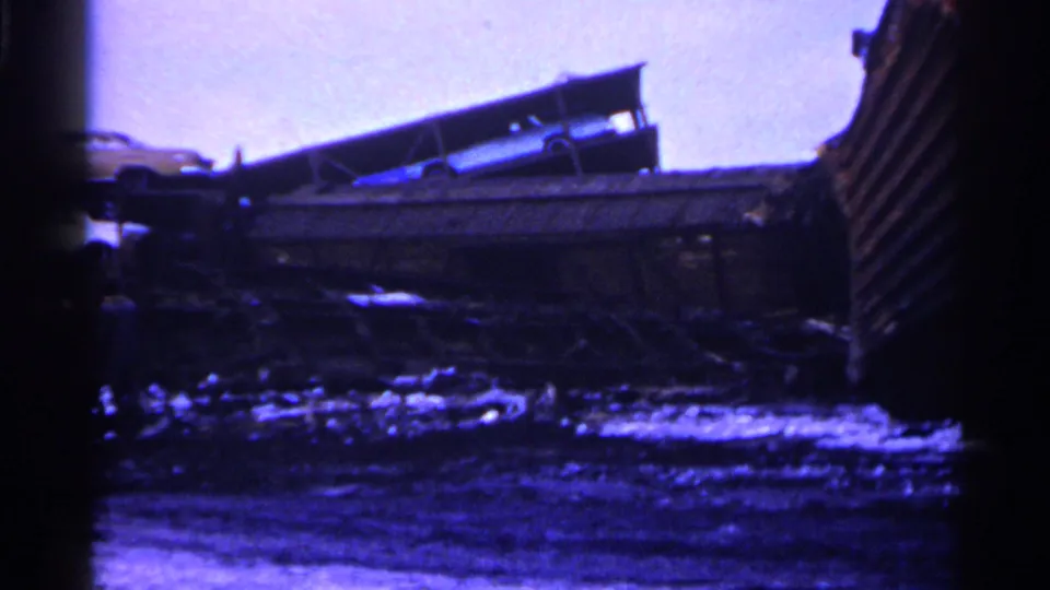 1961 Minnesota derailment aftermath with a car visible above damaged freight cars and dark wreckage below.