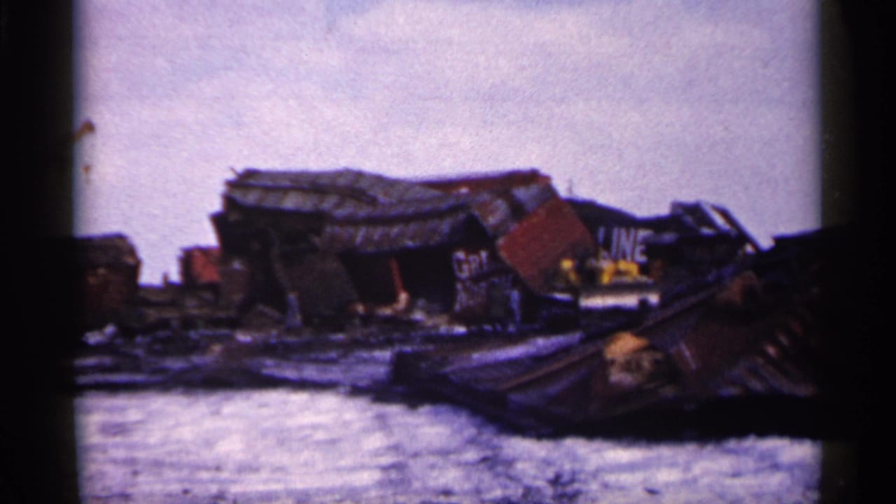 1961 Minnesota 8mm frame showing crushed freight cars and scattered rail wreckage on snowy ground.