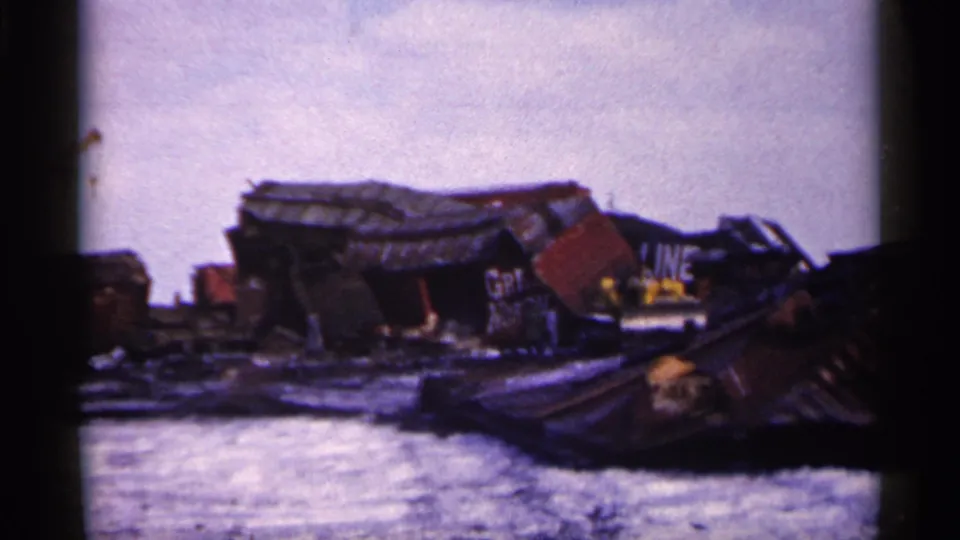 1961 Minnesota 8mm frame showing crushed freight cars and scattered rail wreckage on snowy ground.