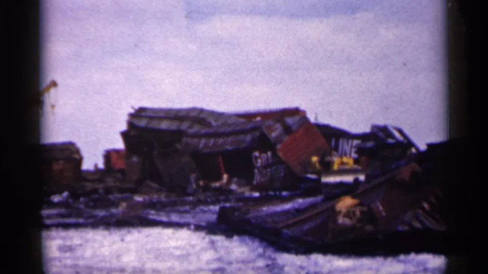 1961 Minnesota derailment aftermath with collapsed freight cars, visible railway lettering, and snow-covered ground.