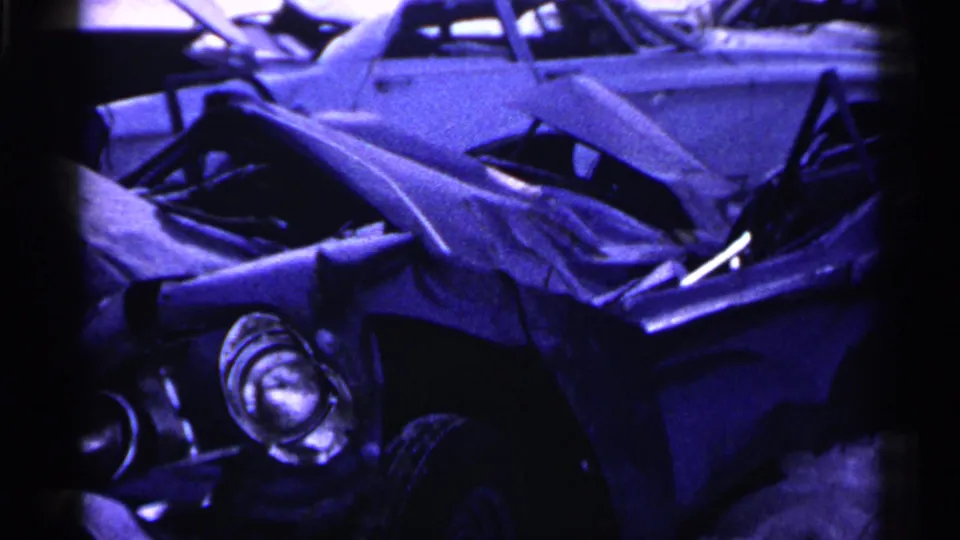 Minnesota 1961 frame showing a crushed car front in the foreground and another classic sedan behind it in the snow.