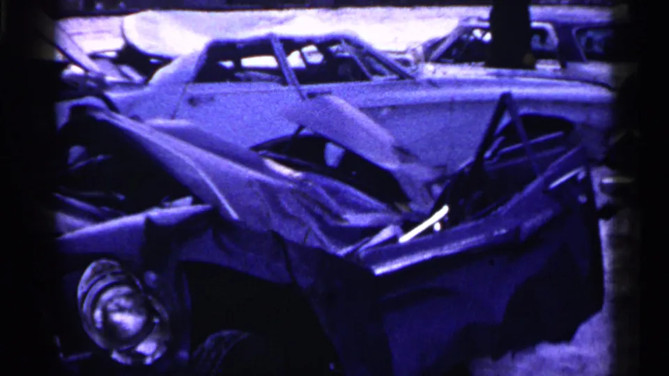 Final 8mm frame of the Minnesota winter accident, showing overlapping wrecked cars, snow, and a light sedan behind the crushed foreground vehicle.