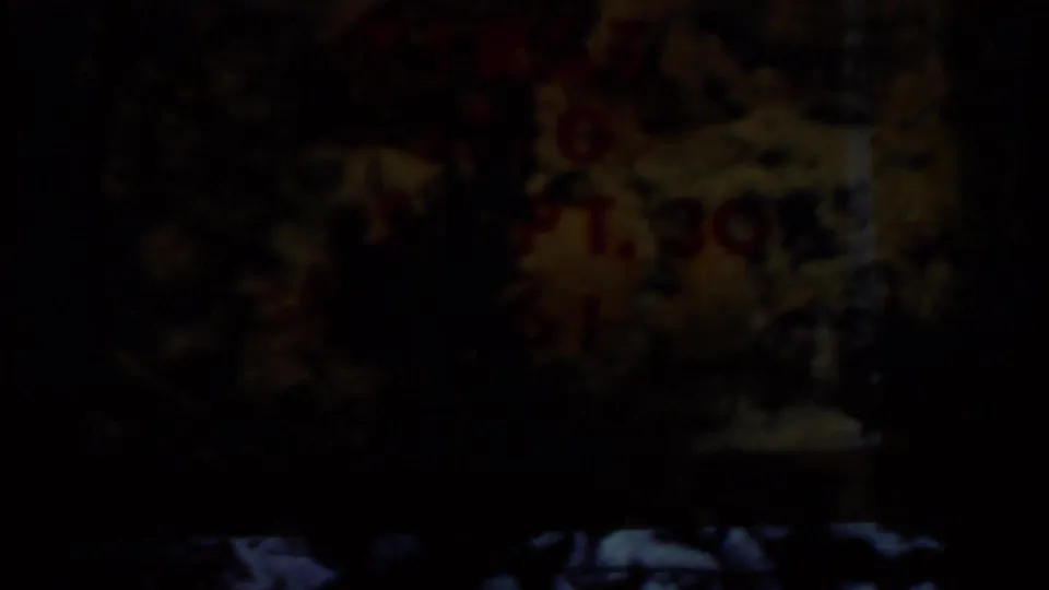 Underexposed 8mm frame with only faint red title-card lettering and dark film borders visible.