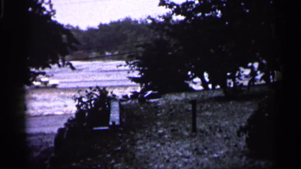 1961 Minnesota roadside view with snow, trees, fence posts, and a blurred vehicle moving past.