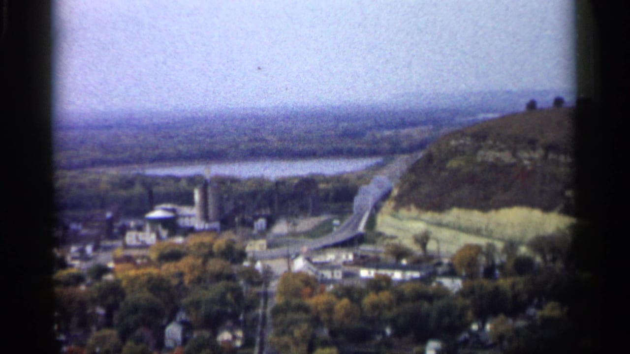Distant town beside a river with a bridge and wooded hillside.