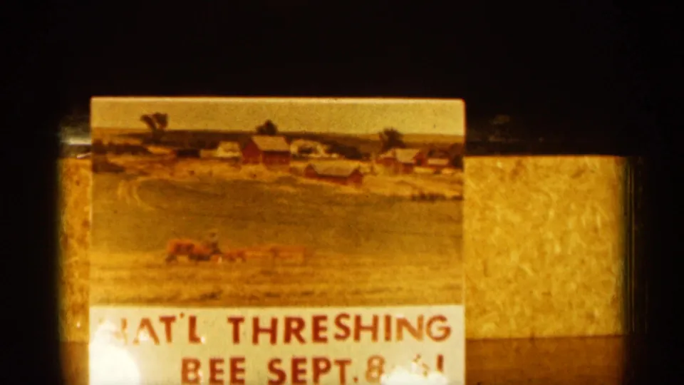 Close view of a National Threshing Bee sign dated September 8, 1961, with a farm field, barns, and agricultural machinery pictured.