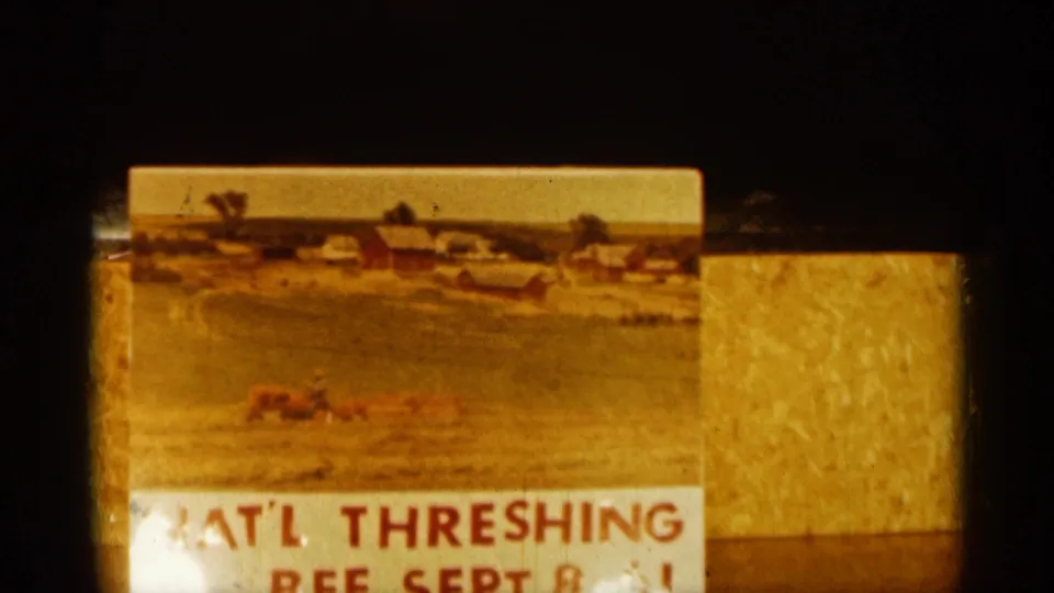 1961 agricultural event sign showing National Threshing Bee lettering, a farm landscape, red barns, and a field scene on a yellow background.