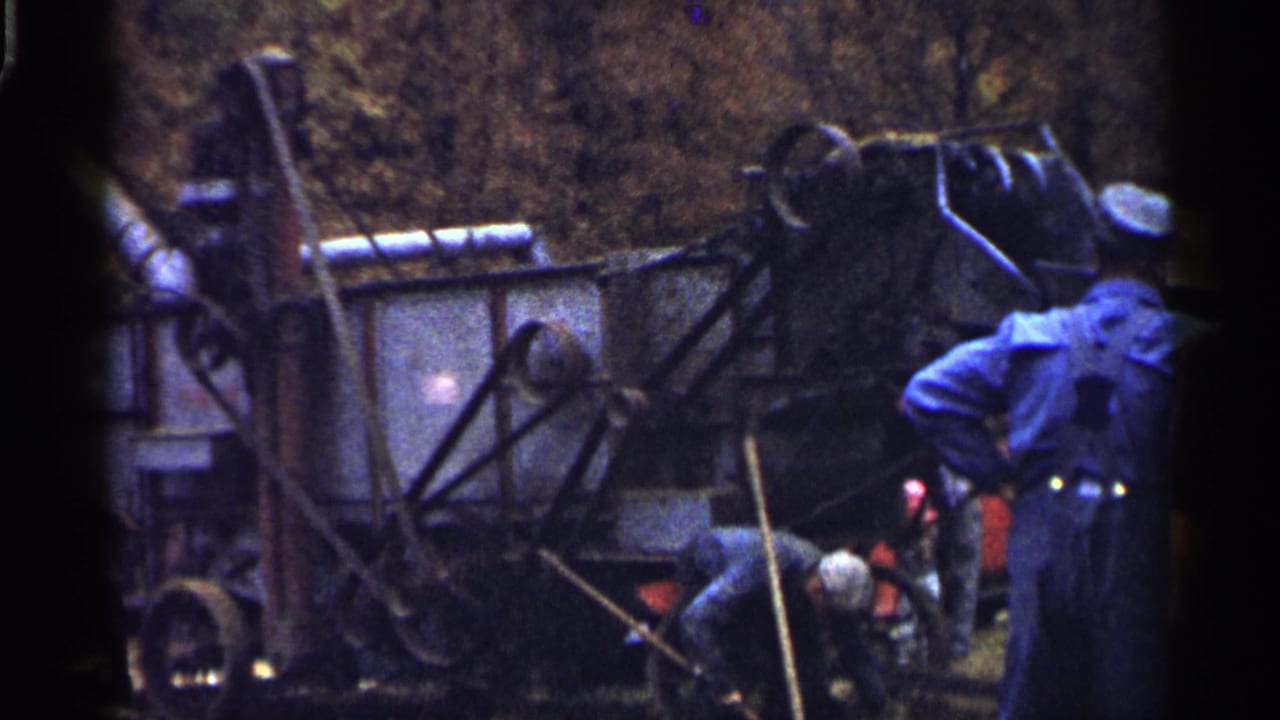 A man stands near machinery while another bends beside the equipment.