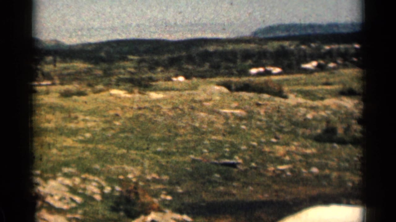 1963 Colorado 8mm frame showing rocky grassland and low hills in a soft, grainy home-movie view.