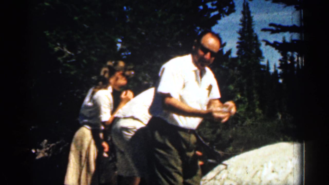 Man holds snow in his hands while family members stand behind him outdoors.