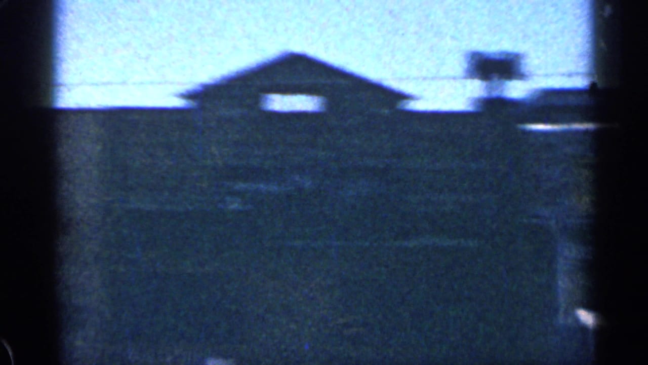 Dark gabled building silhouette with two bright windows and utility lines.