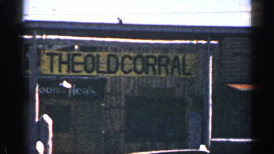 1963 Colorado 8mm frame showing a dark wooden building front with a faded sign reading The Old Corral.