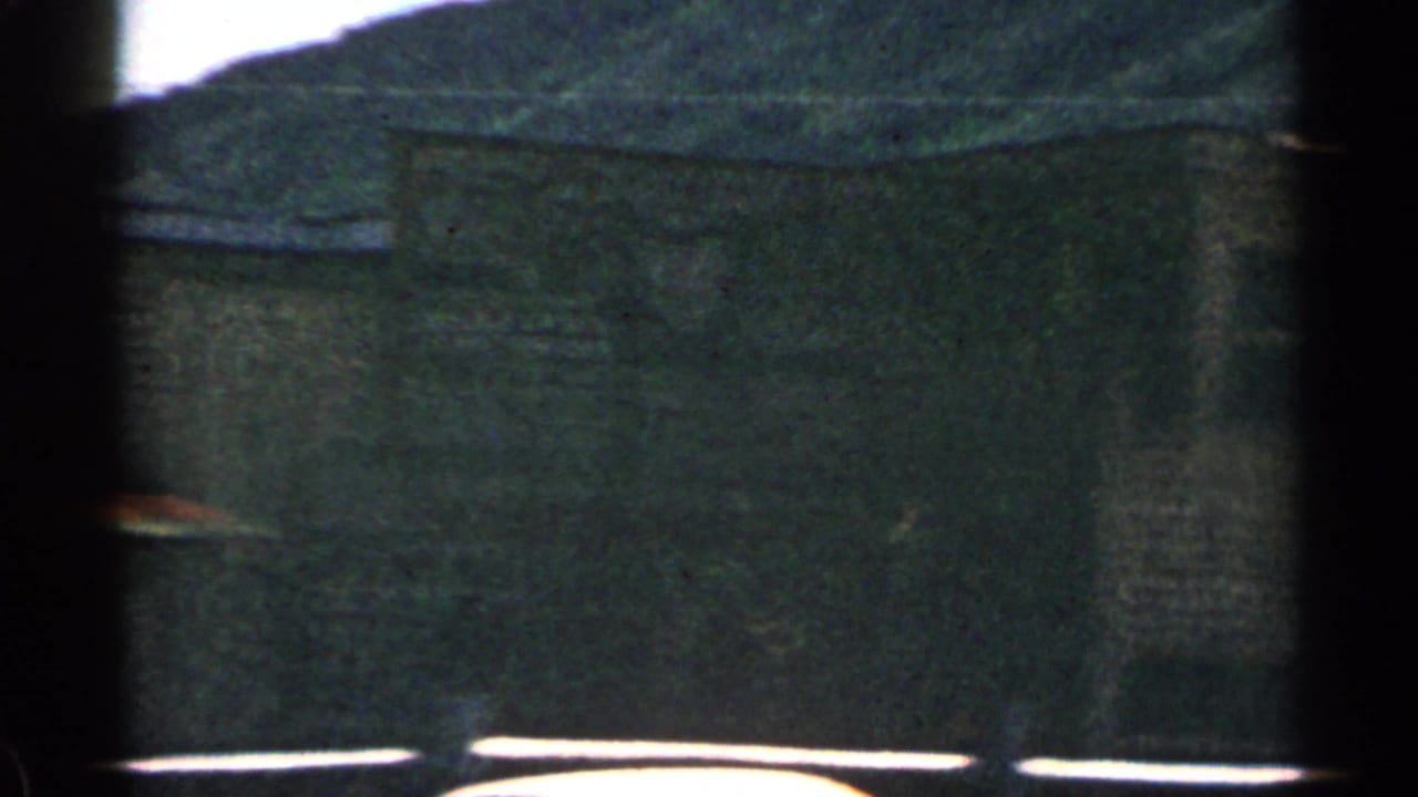 Building facade with partial saloon sign, dark windows, roofline, and hillside behind.