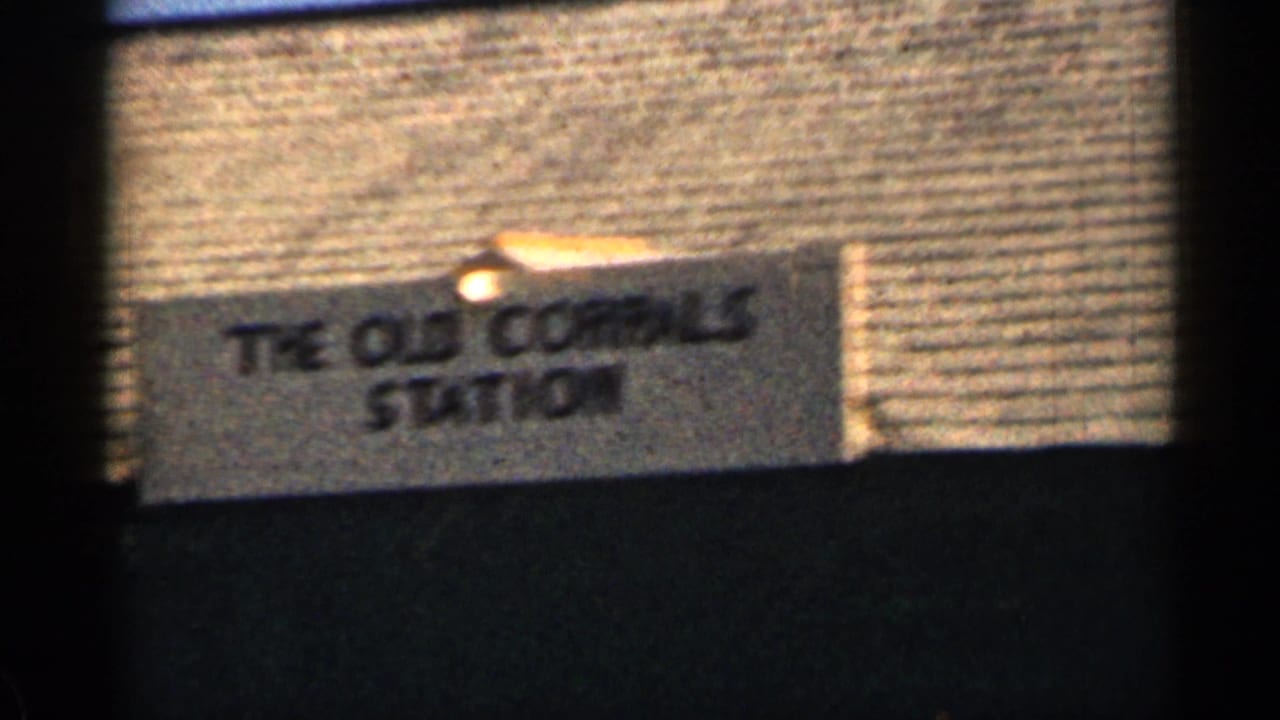 Station sign reading The Old Corrals Station beside a rail scene.
