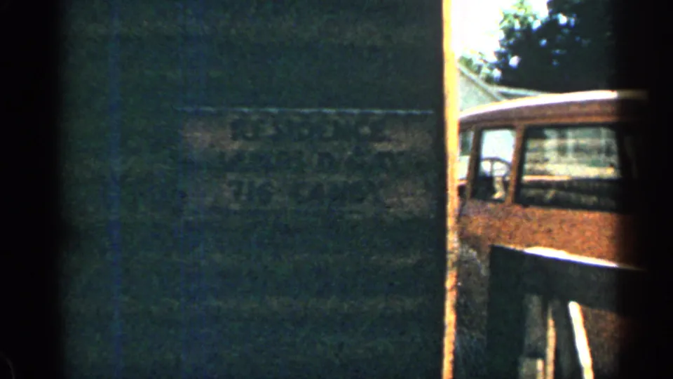 1963 Colorado 8mm frame with a dark interior edge and a partial view of a wooden-sided vehicle through an opening.
