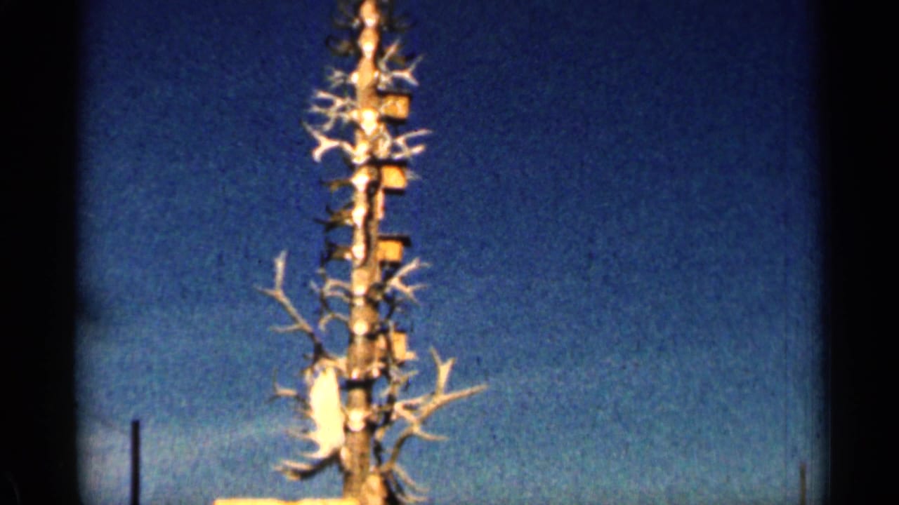 1963 Colorado 8mm frame isolating the upper part of an antler-covered wooden tower beneath clear sky.