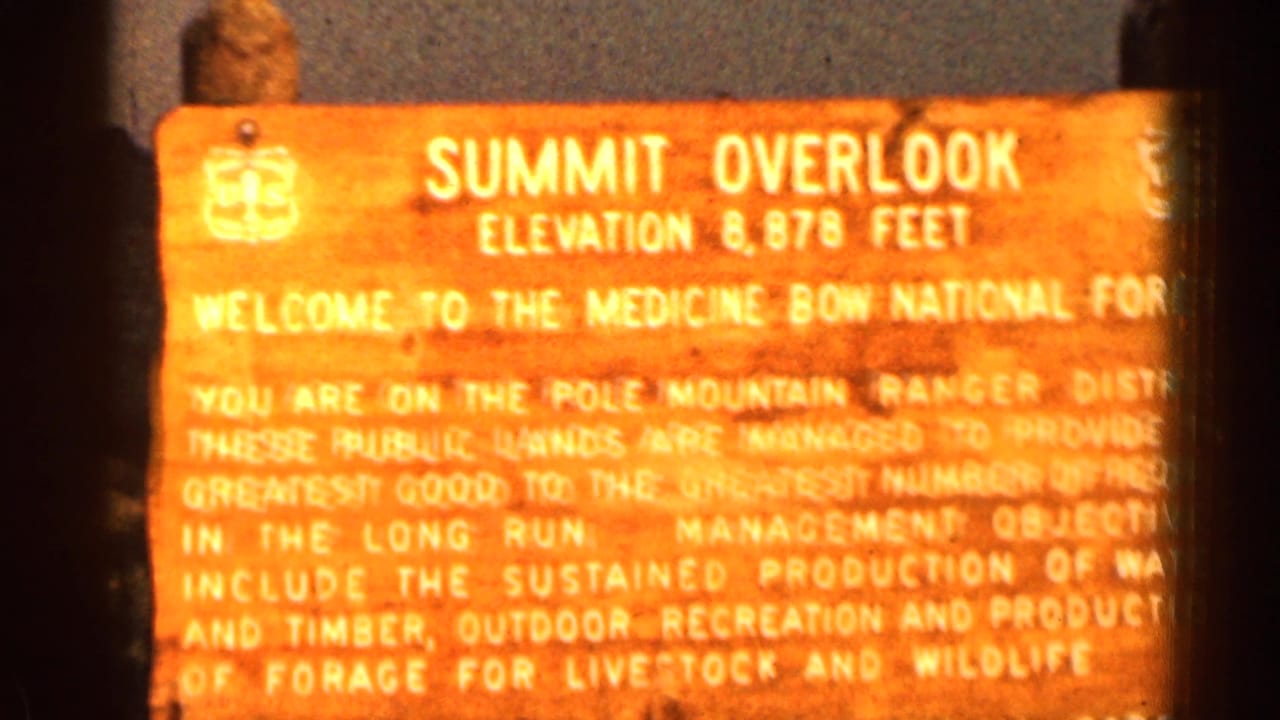 Sunlit wooden Summit Overlook sign with white lettering and dark film-frame edges.