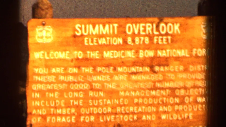 1963 8mm frame of a Summit Overlook sign in Medicine Bow National Forest, partly overexposed and bordered by dark frame edges.