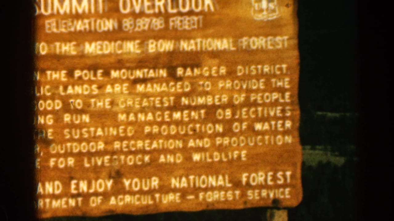 Warm 8mm close-up of the Summit Overlook sign in Colorado, with Medicine Bow National Forest and public lands management text visible.