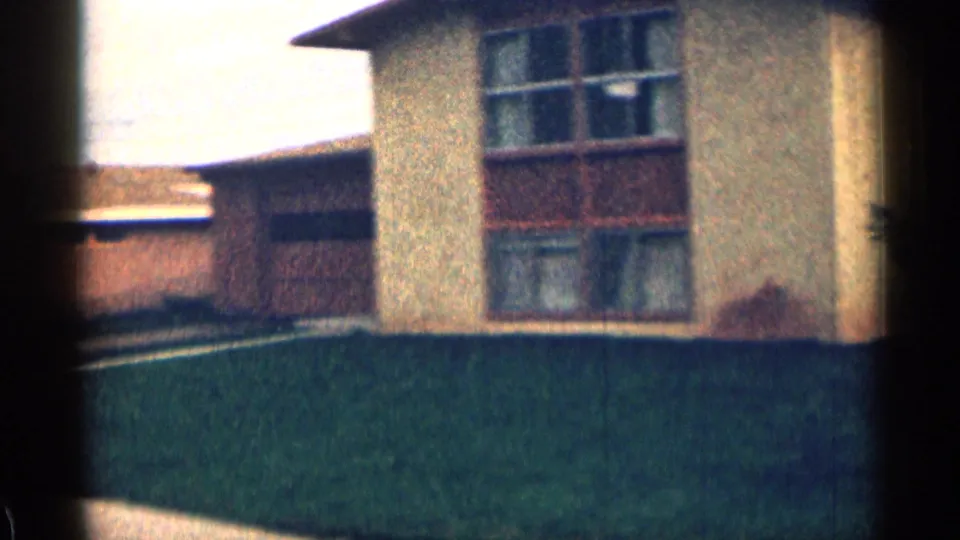 1963 Colorado suburban frame with a house facade, large multi-pane windows, a green lawn, and a lower adjoining or nearby building.