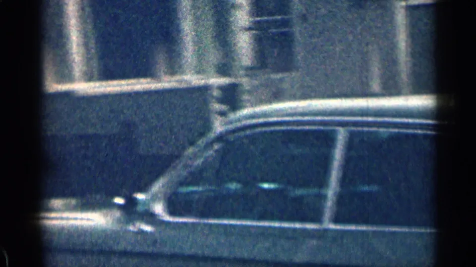 A period automobile appears parked beside the Colorado home exterior, with no person clearly visible in this frame.