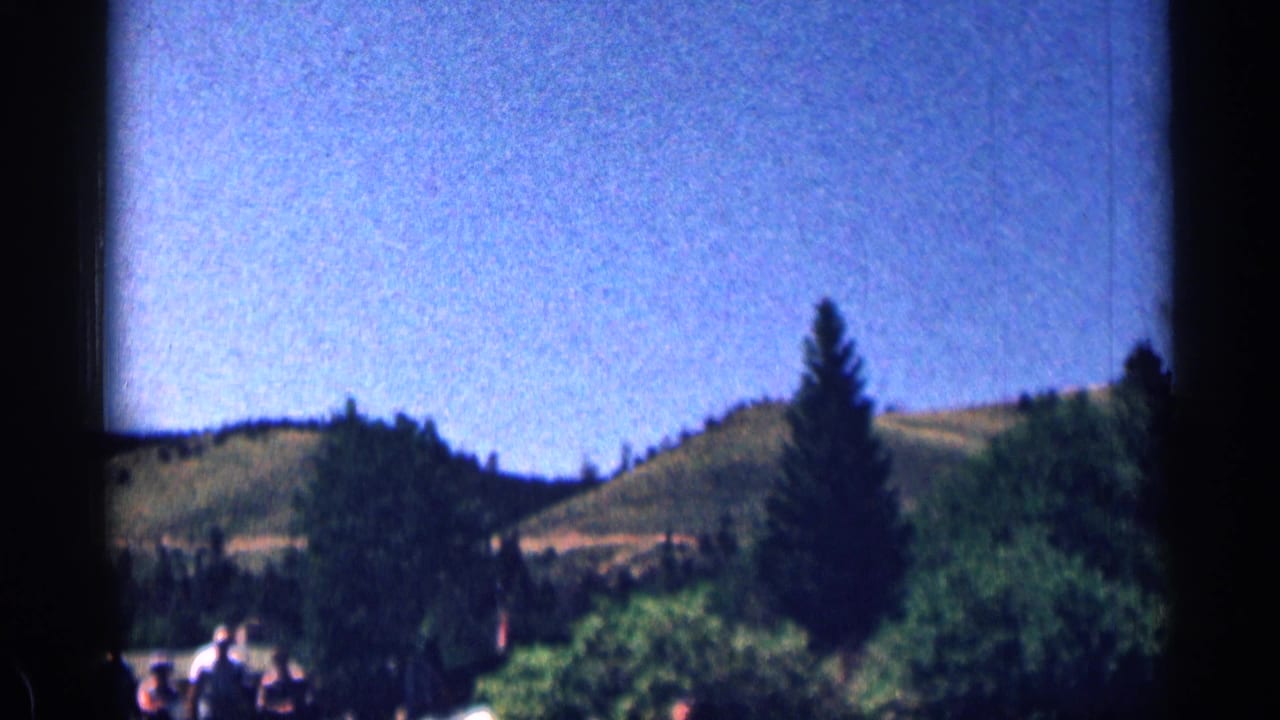 Wooded hills and blue sky with small visitors partly visible at the bottom edge.