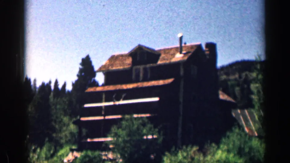 Colorado mountain lodge or visitor building framed by evergreens in saturated 8mm color footage from 1963.