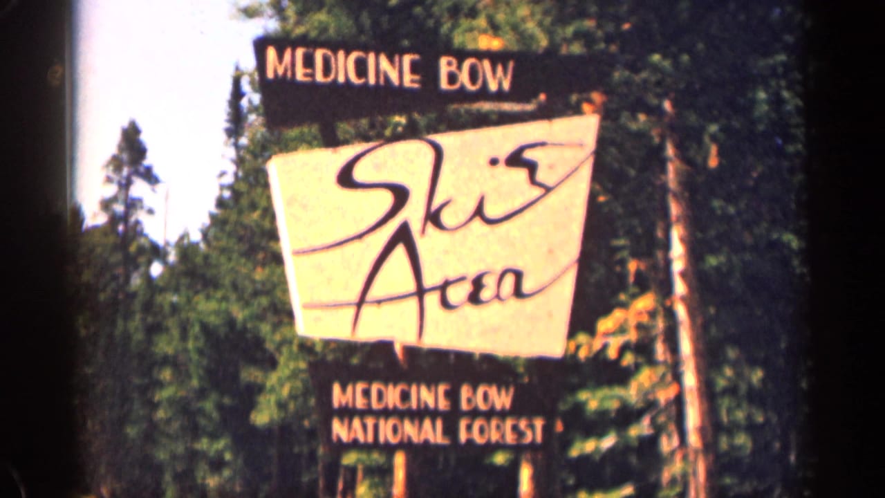 Medicine Bow Ski Area sign among pine trees with national forest wording below.