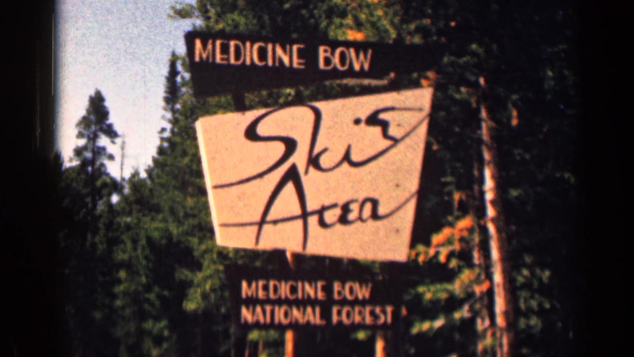Medicine Bow Ski Area sign fills the frame, with pine forest and dark 8mm frame edge visible around it.