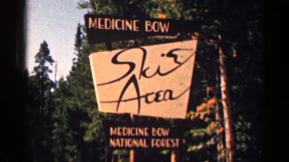 Medicine Bow Ski Area sign fills the frame, with pine forest and dark 8mm frame edge visible around it.