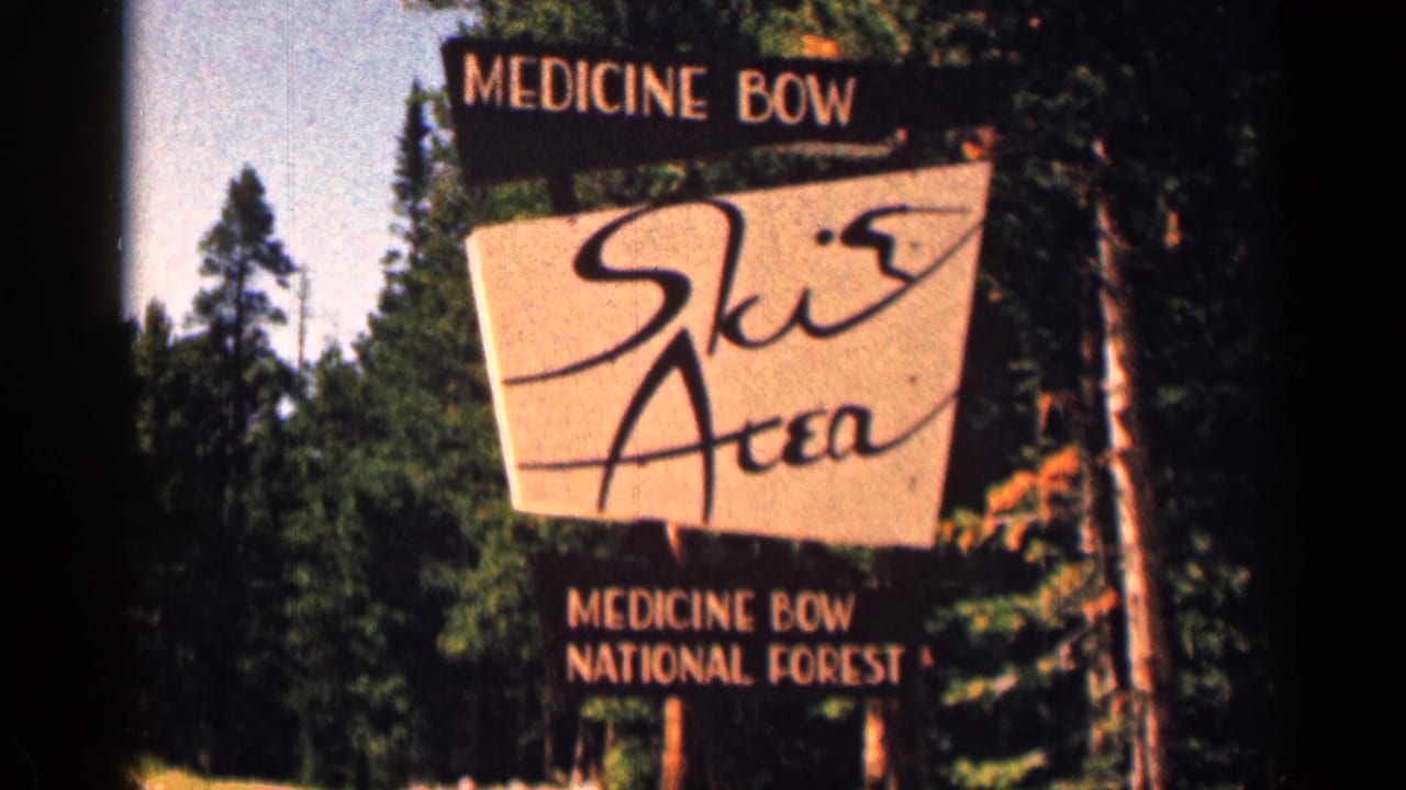 Handheld 8mm view of the Medicine Bow Ski Area sign, with national forest text and tall trees behind it.