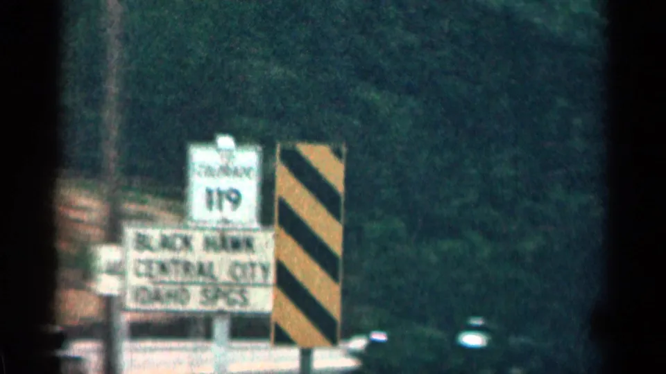 Colorado roadside directional sign for Black Hawk, Central City, and Idaho Springs, with route marker and black-yellow hazard board.