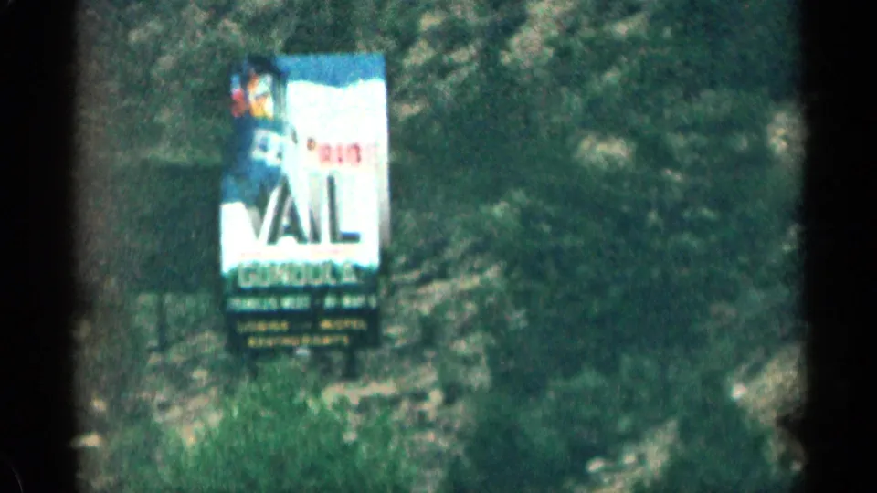1963 Colorado 8mm frame with a roadside Ride Vail gondola billboard and skier graphic set against a mountain slope.