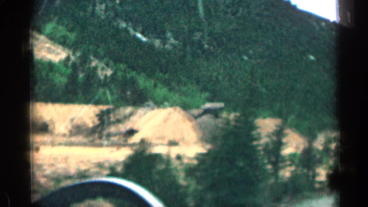 Mountain excavation area seen through dark vehicle-window edges.