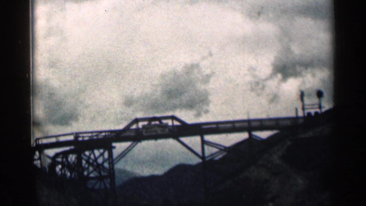 Steel bridge spans the frame with a small mining sign visible.