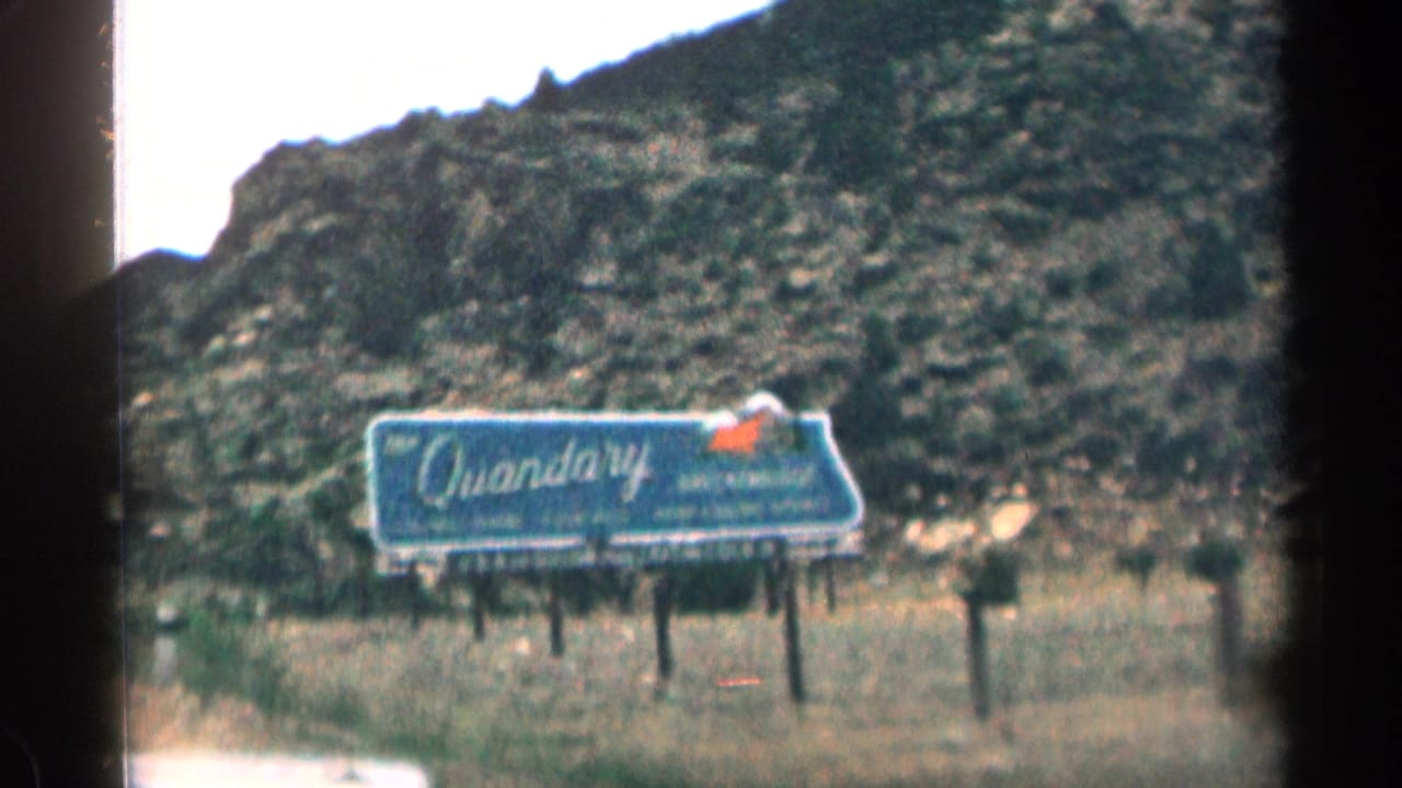 Quandary billboard along a rocky roadside landscape.
