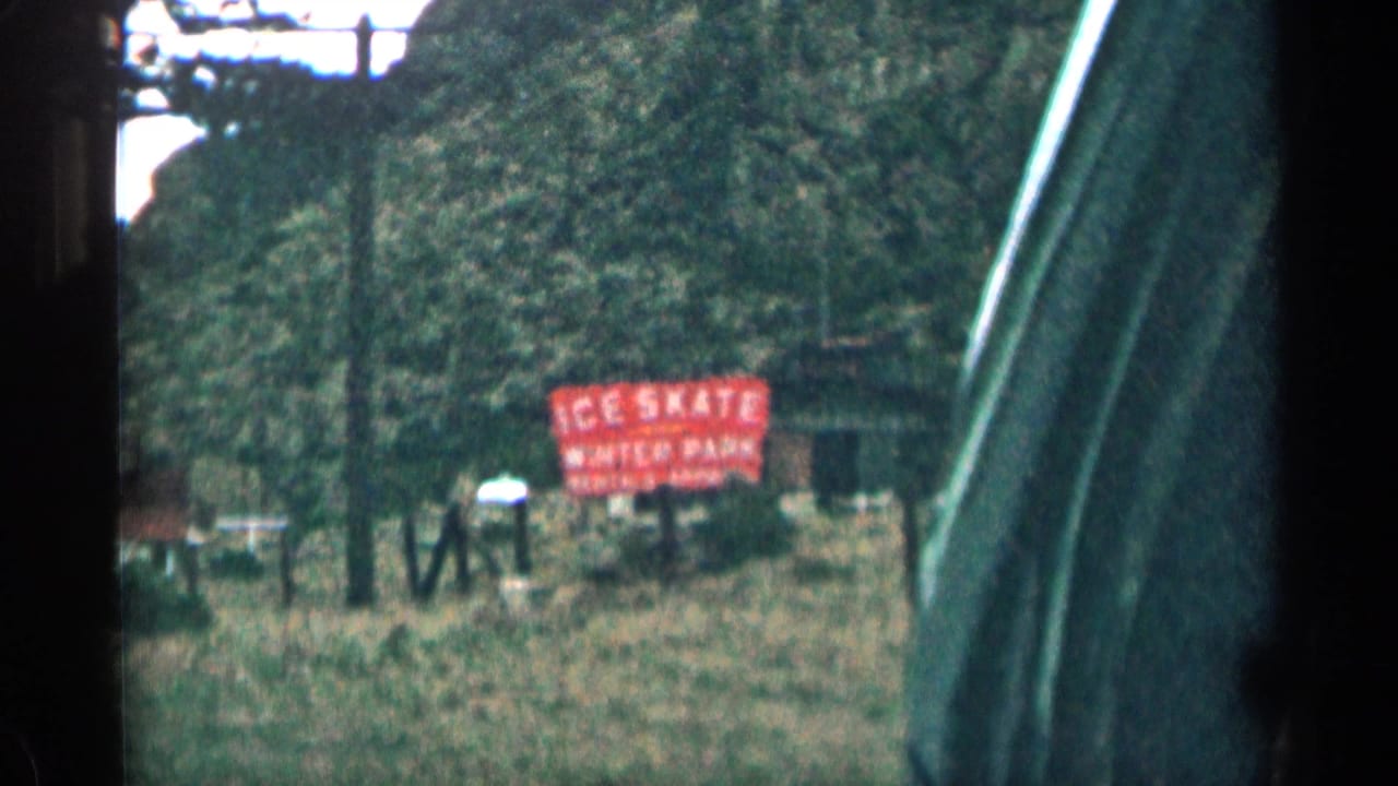 Red ice skate rental sign beside a rural mountain road.