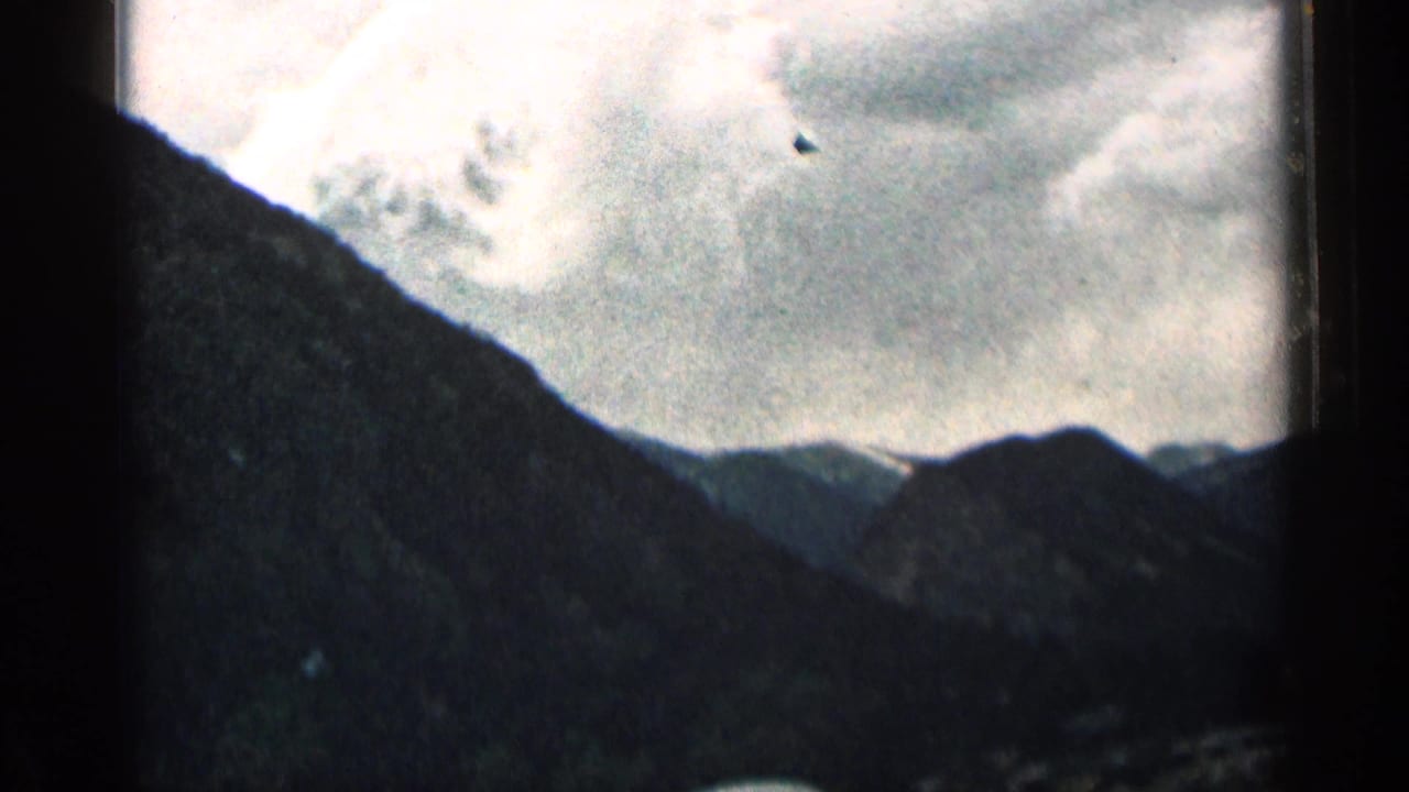 Colorado mountain landscape seen from a moving vehicle, with a steep dark slope and cloudy sky.