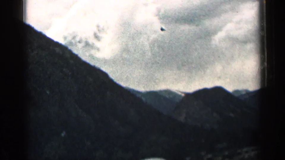 Colorado mountain landscape seen from a moving vehicle, with a steep dark slope and cloudy sky.