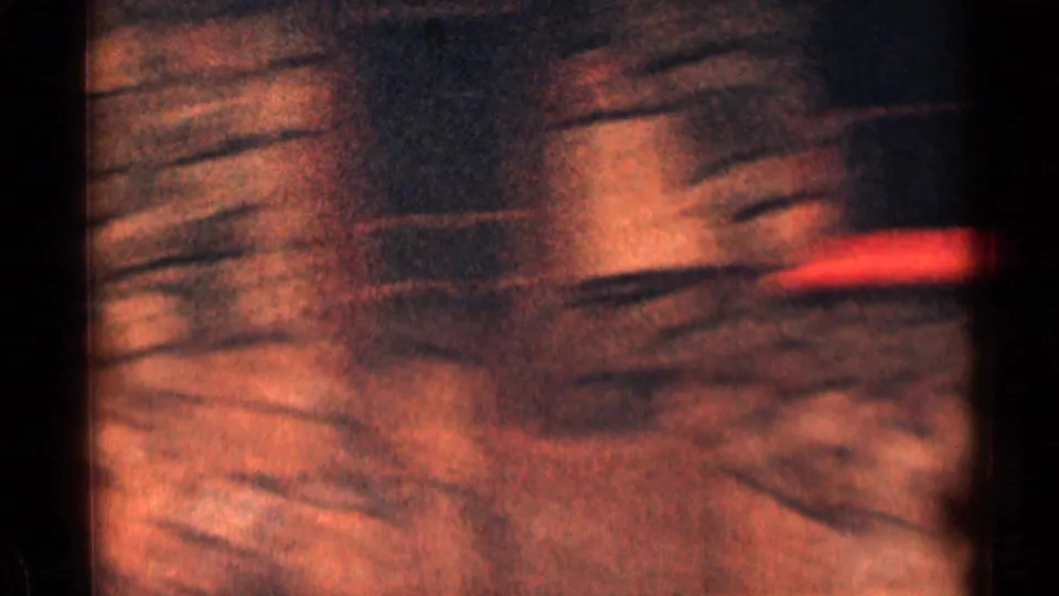 Motion-blurred 8mm frame with reddish roadside or vehicle detail, dark gate edge, and streaked texture from quick camera movement.