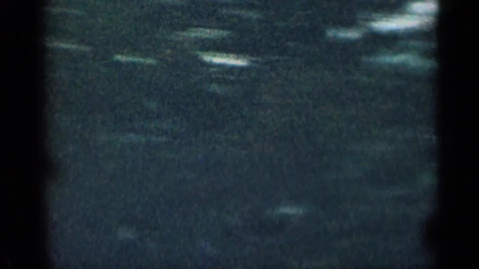 Very dark 8mm frame from the Colorado mountain clip, with faint pale streaks and obscured landscape texture.