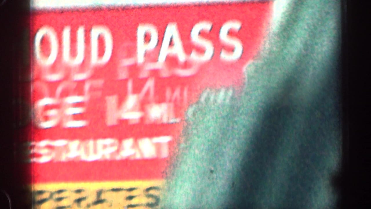 Blurred red roadside sign with white lettering and dark mountain background.