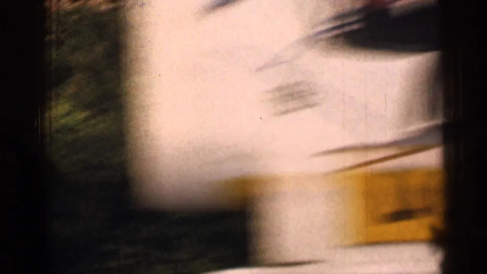 Soft, overexposed 1963 Colorado travel frame showing a pale roadside surface or structure blurred by vehicle movement.