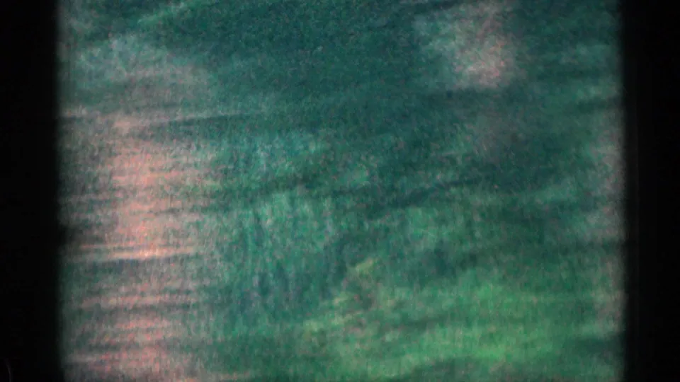 1963 Colorado road-view frame with blurred green terrain, darker hillside shapes, and a home-movie look from motion and grain.