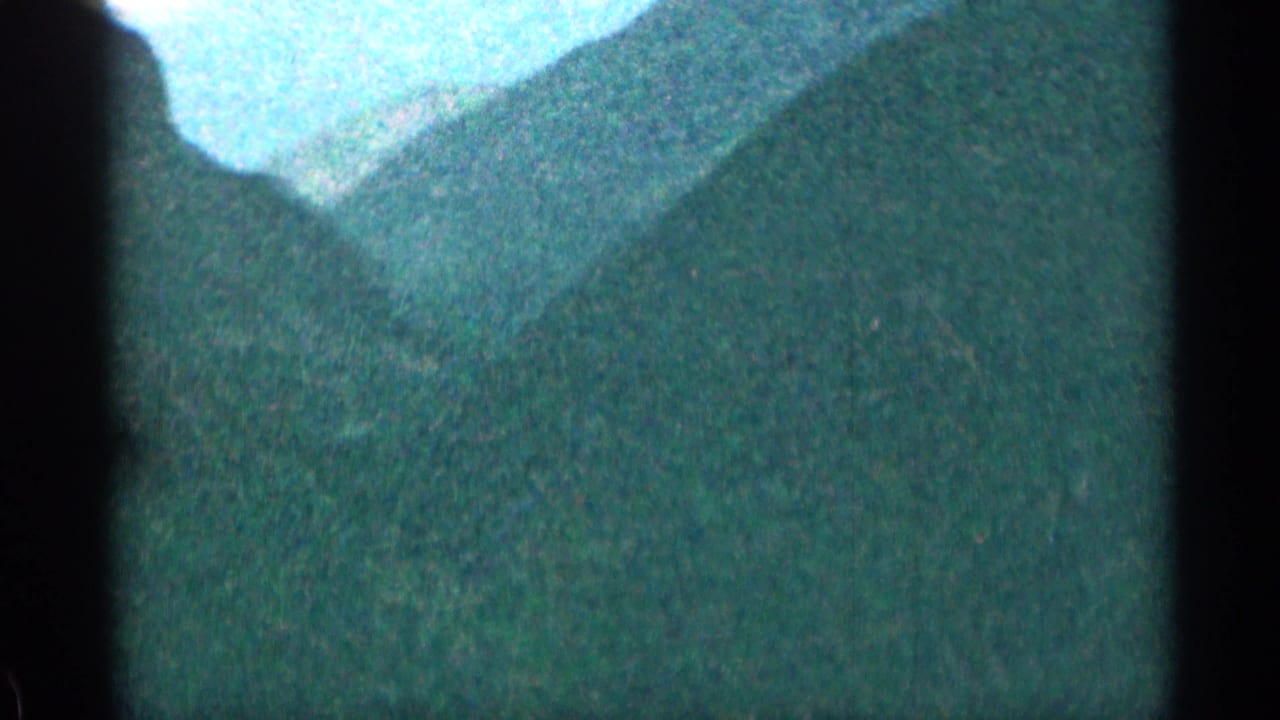 Forested mountain slope seen through dark vertical vehicle framing.