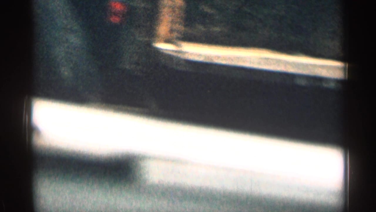 Soft, grainy 1963 Colorado 8mm frame showing a blurred road edge or vehicle surface during travel.