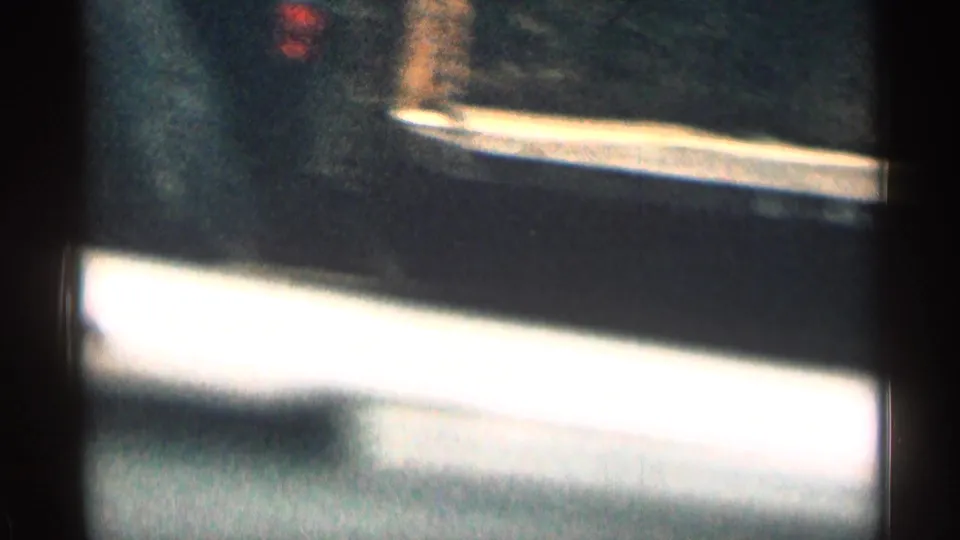 Soft, grainy 1963 Colorado 8mm frame showing a blurred road edge or vehicle surface during travel.